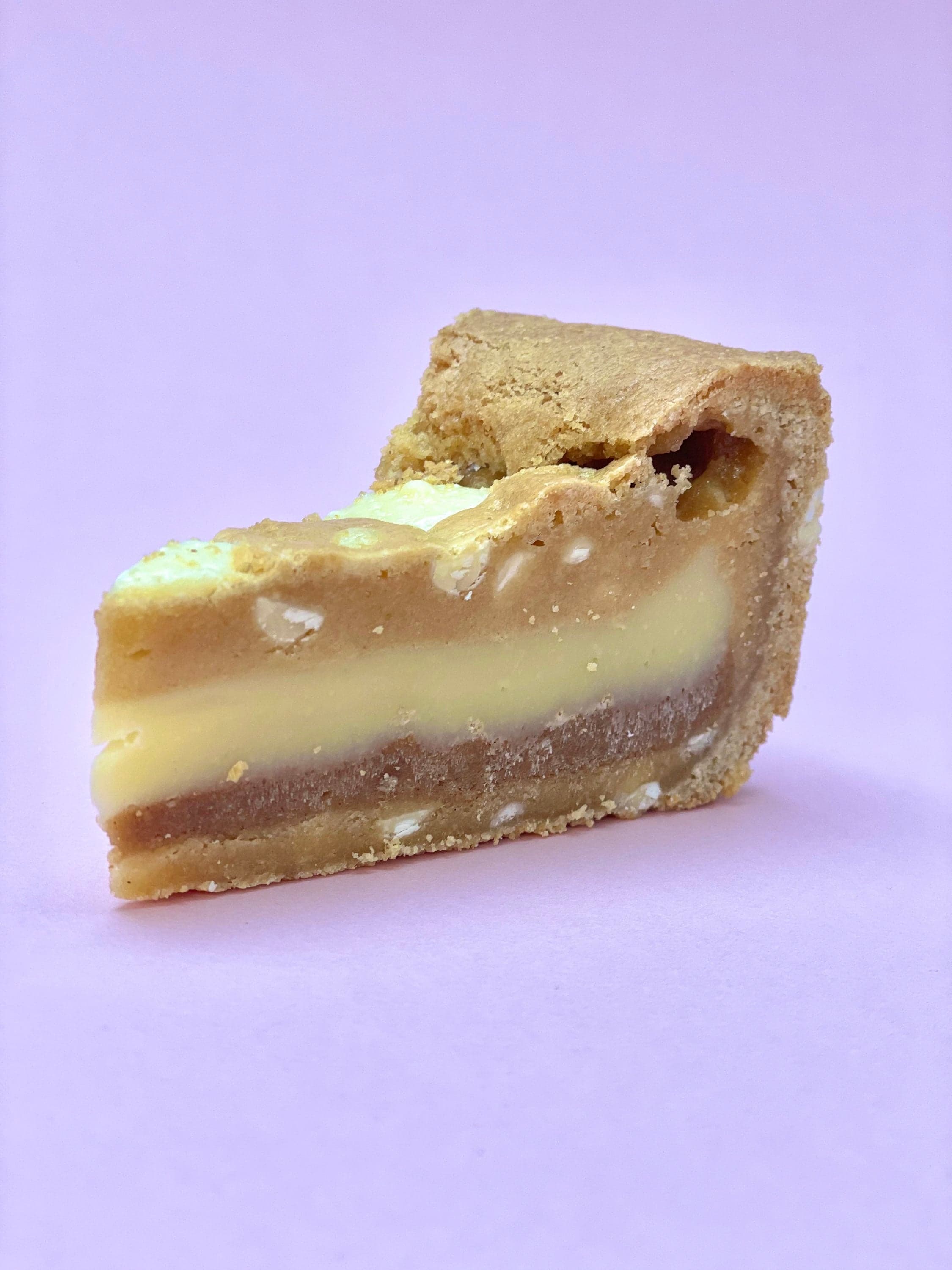 Cross-section of a Biscoff and white chocolate cookie pie slice on a lilac background